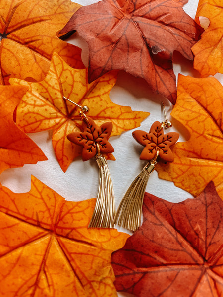 Earrings with leaf design on a bed of orange leaves
