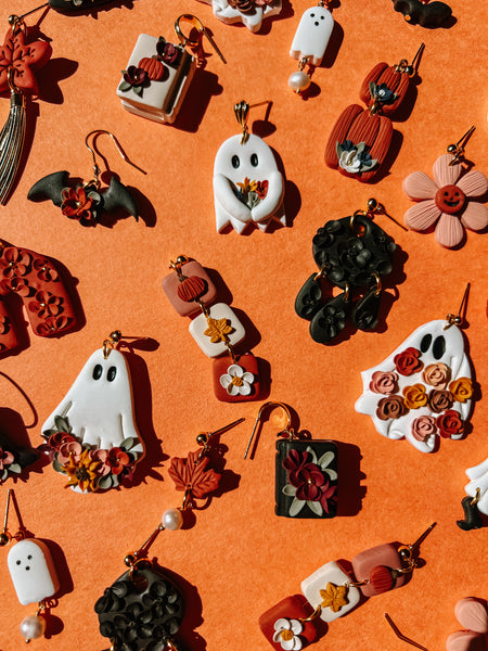 Assorted Halloween-themed earrings on an orange background